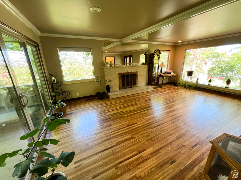 Unfurnished living room with wood finished floors, ornamental molding, and a high end fireplace