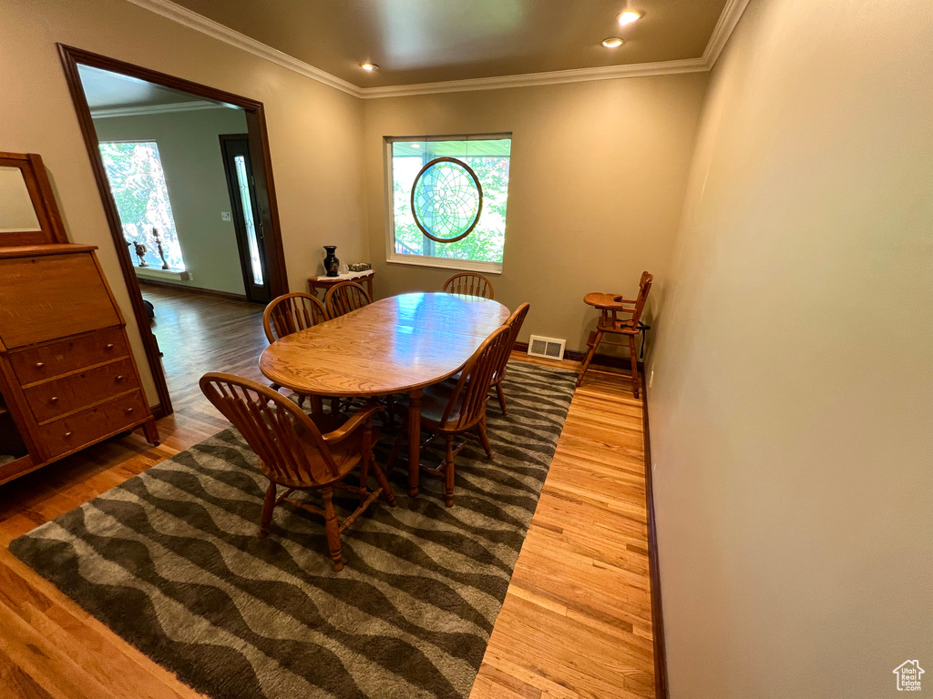Dining room with wood finished floors, plenty of natural light, crown molding, and recessed lighting