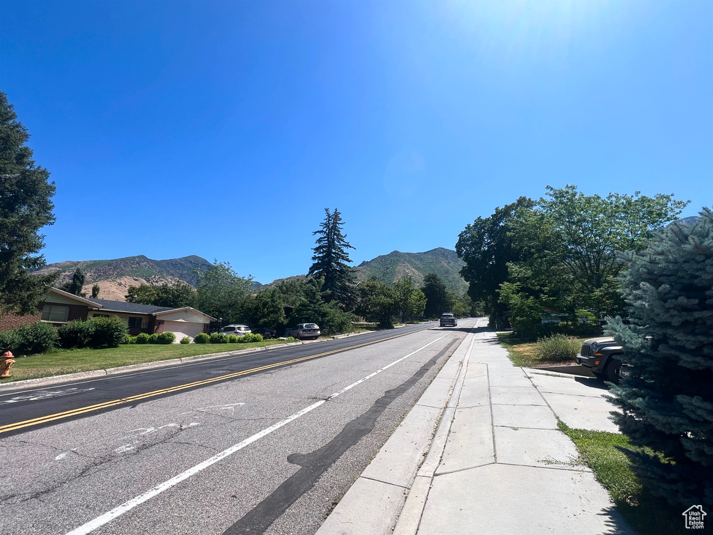View of asphalt street featuring a mountain view, curbs, and sidewalks