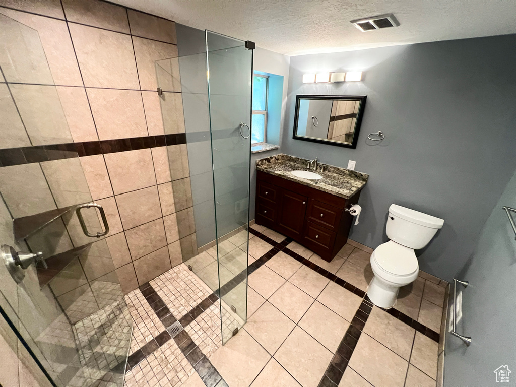 Full bath featuring tile patterned floors, vanity, a stall shower, a textured ceiling, and inlaid floor details