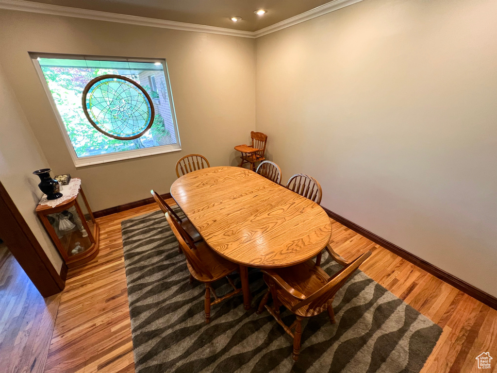 Dining space with light wood-type flooring and ornamental molding