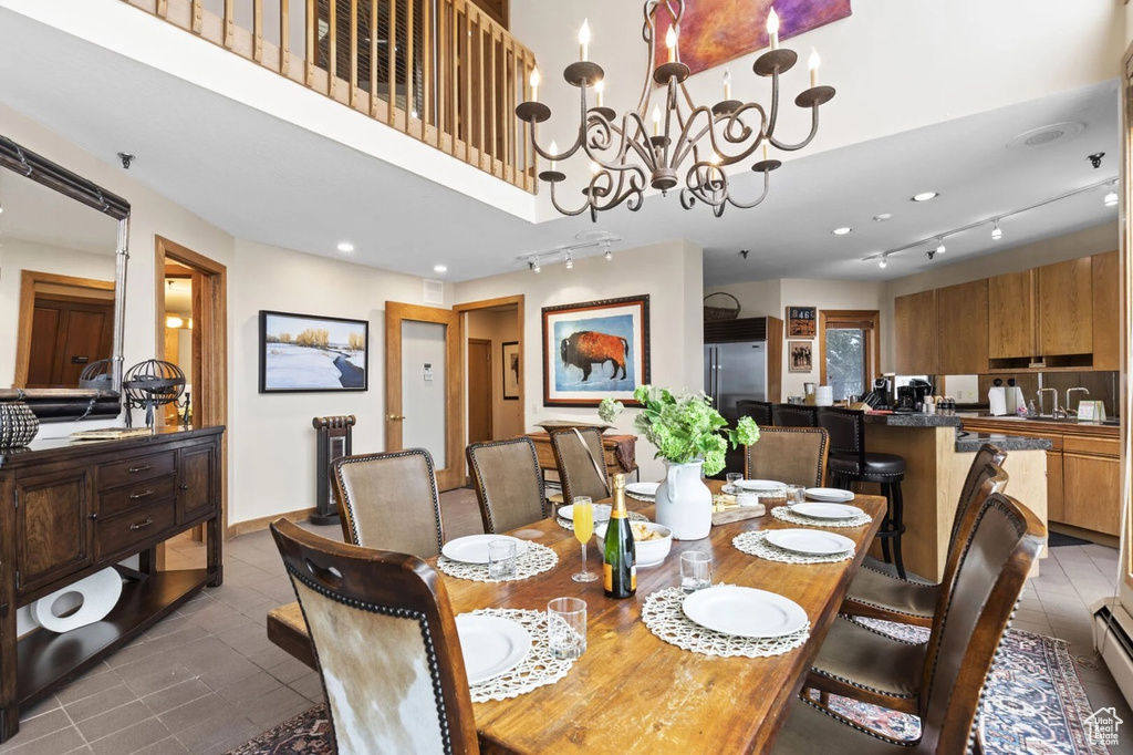Dining area featuring rail lighting, dark tile patterned floors, and a chandelier