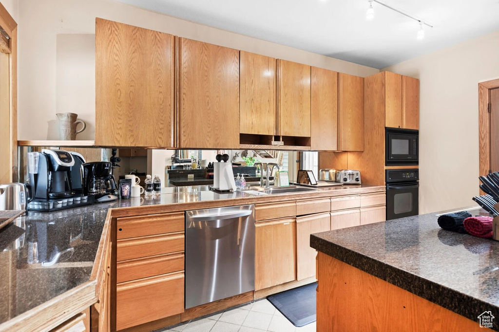 Kitchen with black appliances, track lighting, and light tile patterned flooring