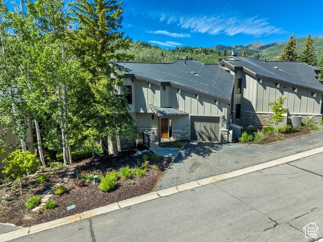 View of front of home with board and batten siding, driveway, stone siding, an attached garage, and a mountain view