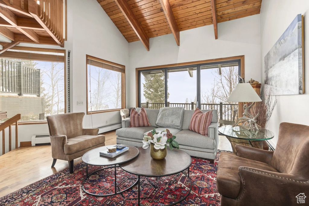 Living area with a baseboard radiator, a wood ceiling with exposed beams, wood finished floors, and high vaulted ceiling