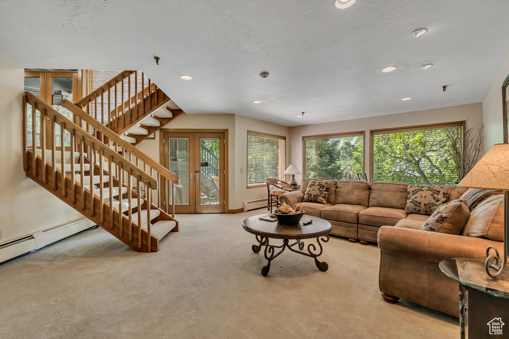 Carpeted living area featuring baseboard heating, stairway, recessed lighting, a textured ceiling, and french doors