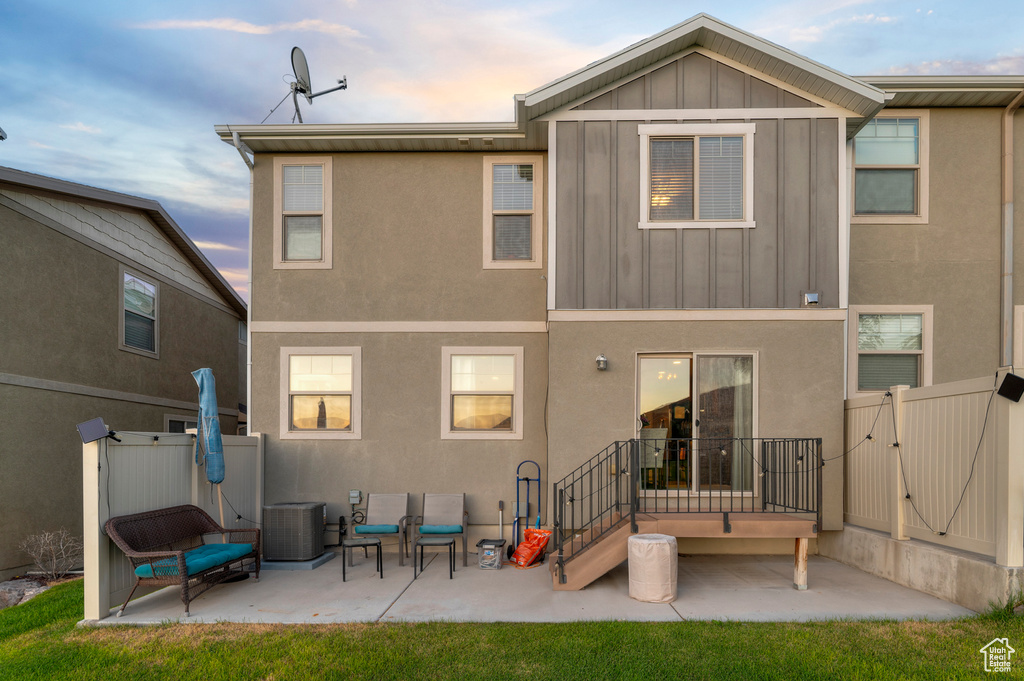 Rear view of property with a gate, board and batten siding, a patio, and stucco siding
