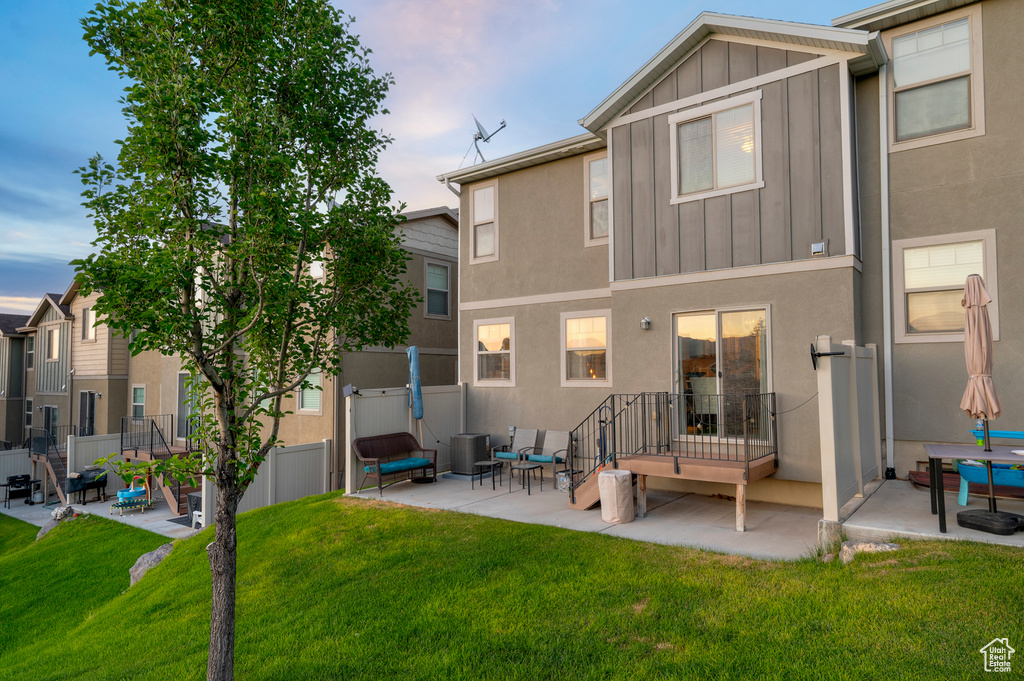 Rear view of house featuring a patio area, board and batten siding, and stucco siding