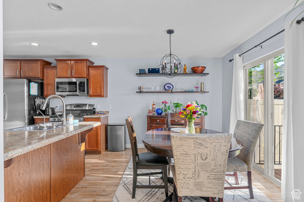 Kitchen featuring stainless steel appliances, brown cabinets, light wood finished floors, a chandelier, and recessed lighting