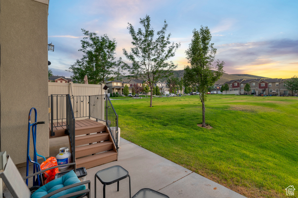 Patio terrace at dusk featuring a residential view and a lawn