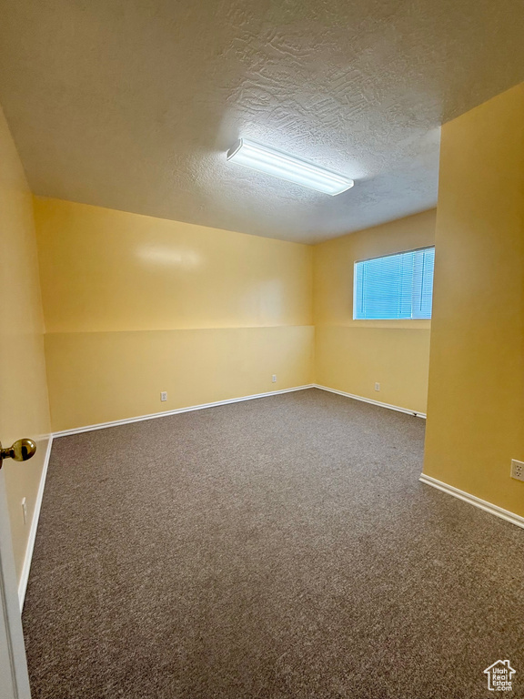 Empty room with a textured ceiling and carpet