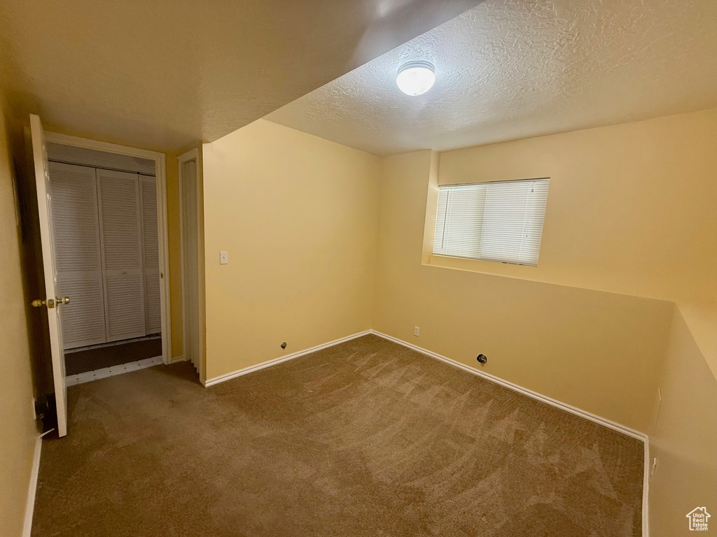 Unfurnished bedroom featuring carpet, a textured ceiling, and a closet