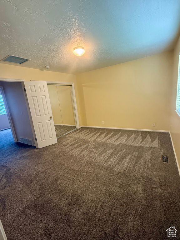 Spare room with dark carpet and a textured ceiling