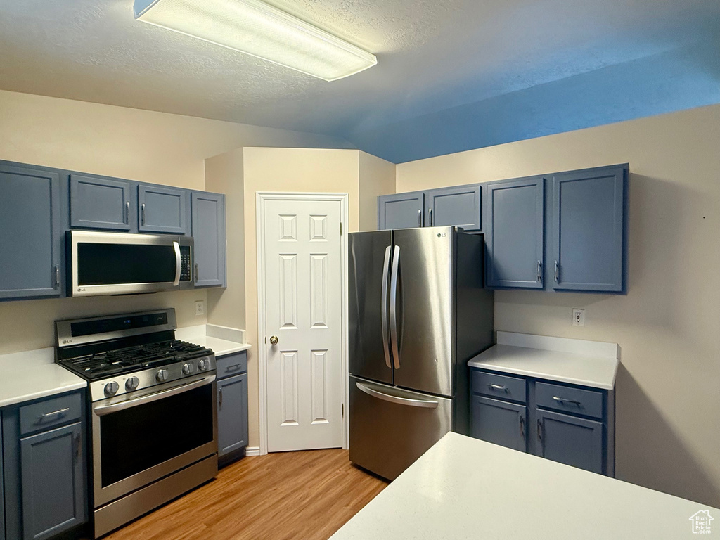 Kitchen featuring stainless steel appliances, light wood-style flooring, light countertops, a textured ceiling, and gray cabinets
