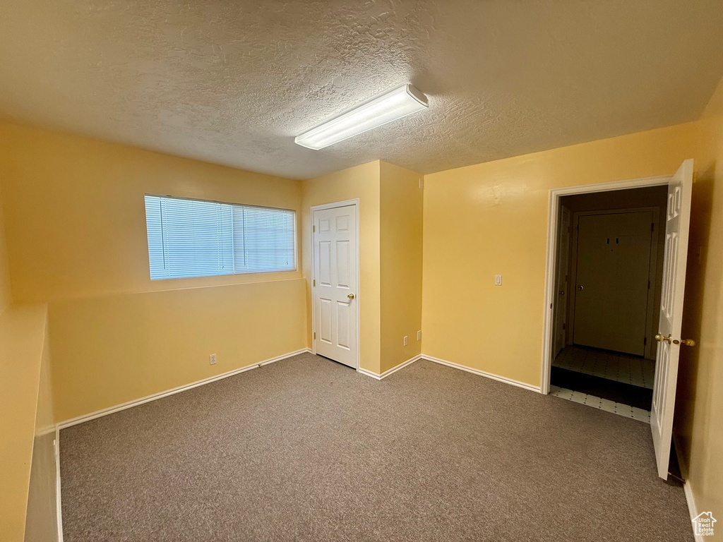 Unfurnished bedroom with a textured ceiling and carpet flooring