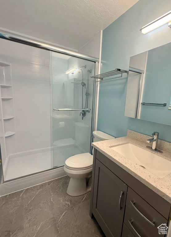 Full bathroom with vanity, a shower stall, and marble look tiles