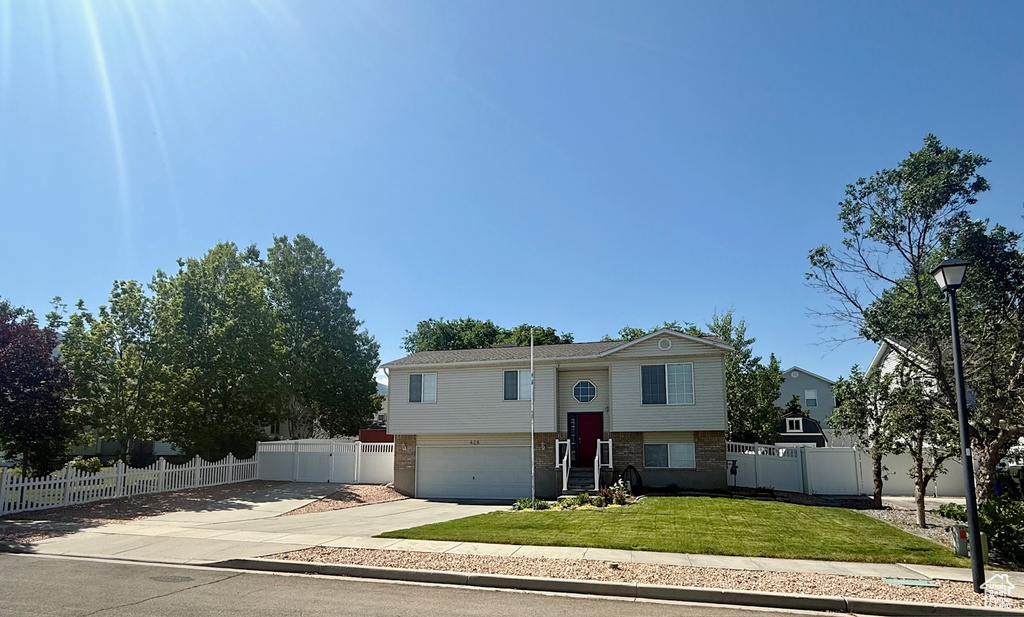 Raised ranch featuring concrete driveway, brick siding, and an attached garage