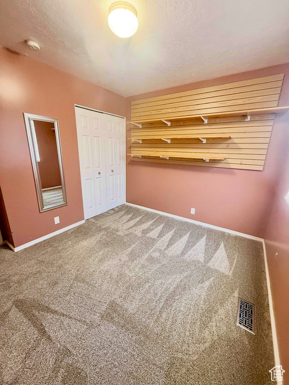 Unfurnished bedroom featuring carpet, a closet, and a textured ceiling