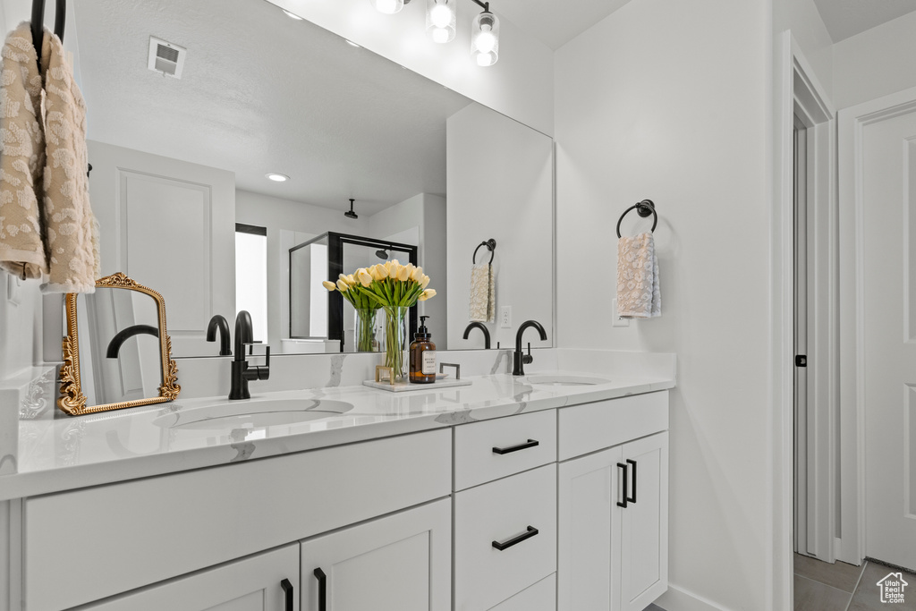Full bathroom featuring double vanity and a shower stall