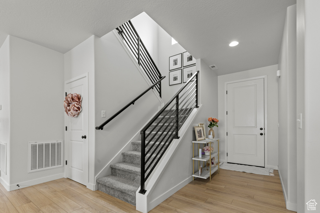 Foyer featuring light wood-type flooring, stairs, and recessed lighting