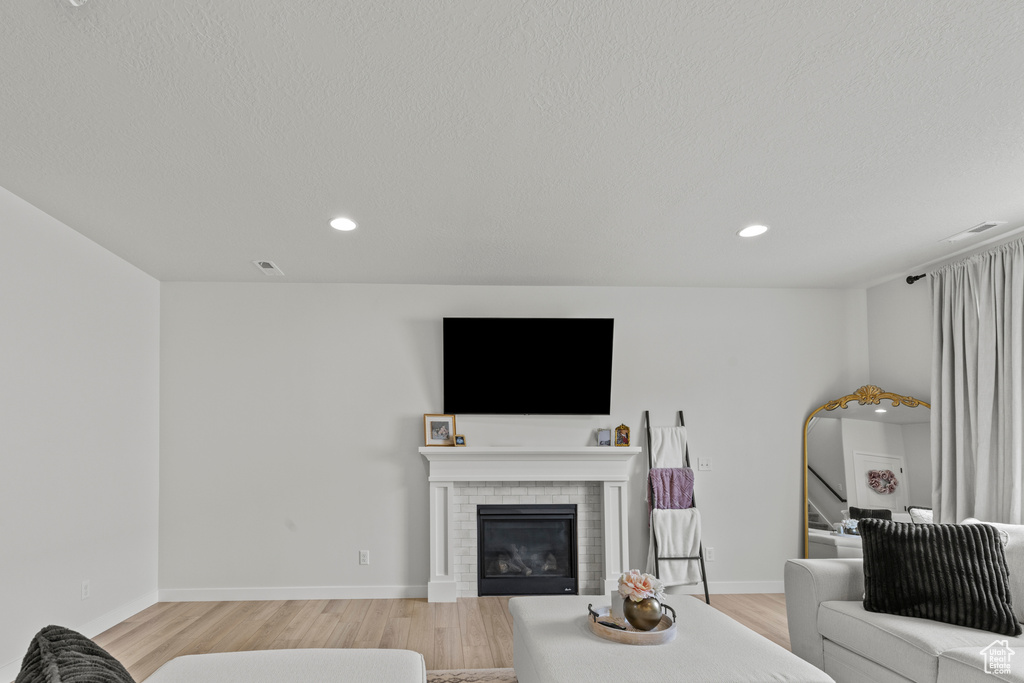 Living area featuring light wood-style floors, a brick fireplace, and recessed lighting
