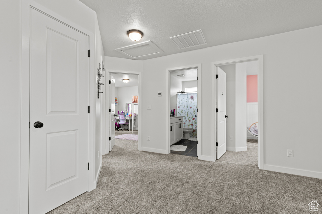 Bedroom with attic access, carpet floors, ensuite bathroom, and a textured ceiling