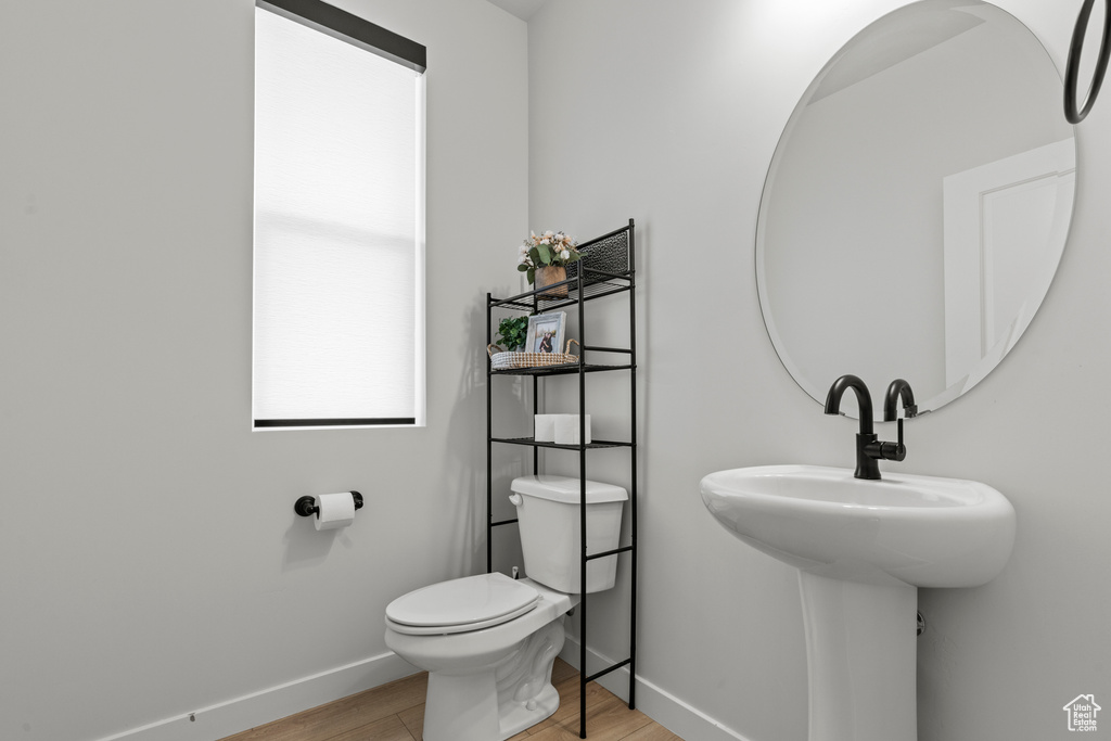 Half bath with wood finished floors and baseboards