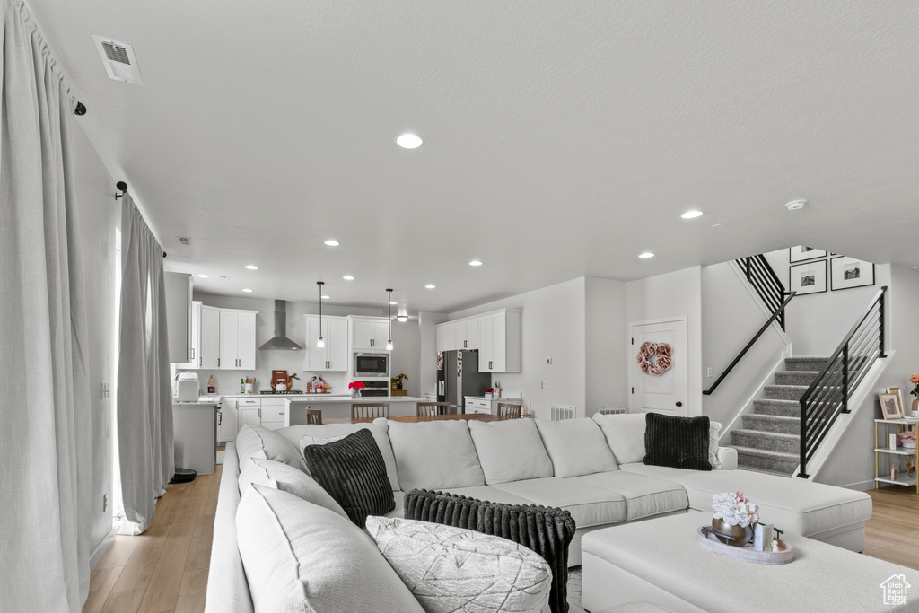 Living room featuring light wood finished floors, recessed lighting, and stairway