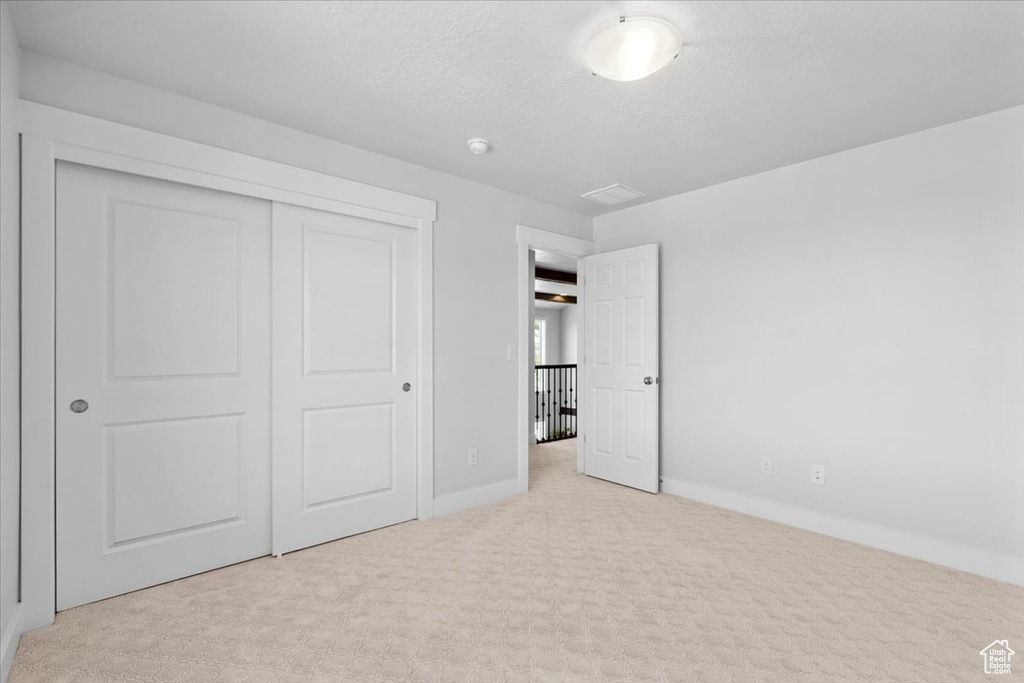 Unfurnished bedroom with carpet floors, a closet, and a textured ceiling