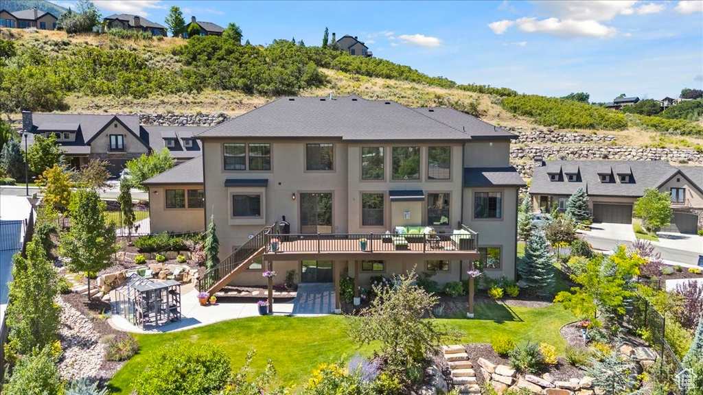 Back of property with a wooden deck, stucco siding, a residential view, and a lawn