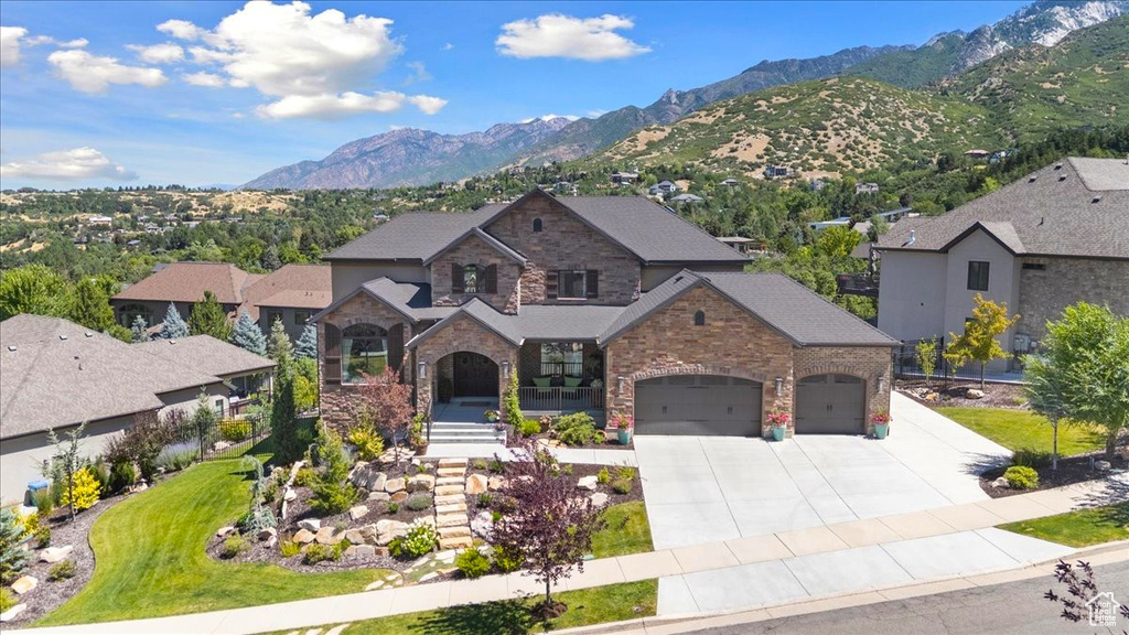 View of front of property with concrete driveway, a garage, a mountain view, and stone siding