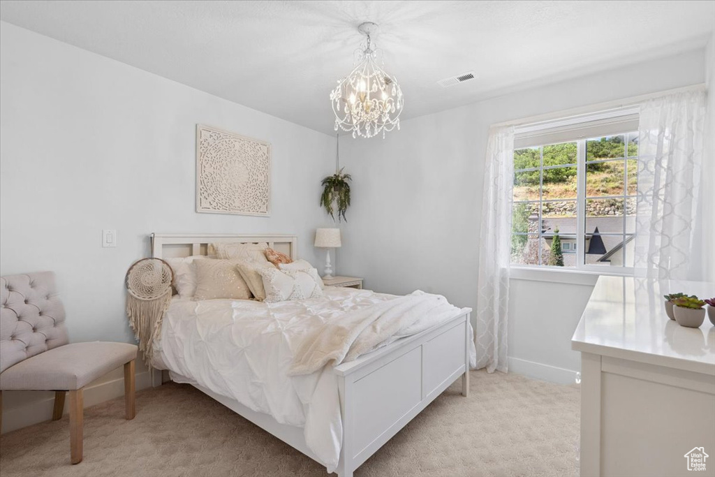 Bedroom with light colored carpet and a chandelier