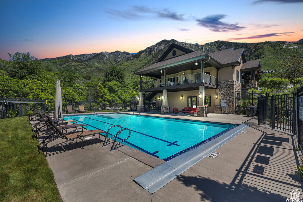 Pool at dusk featuring a patio, a community pool, and a mountain view