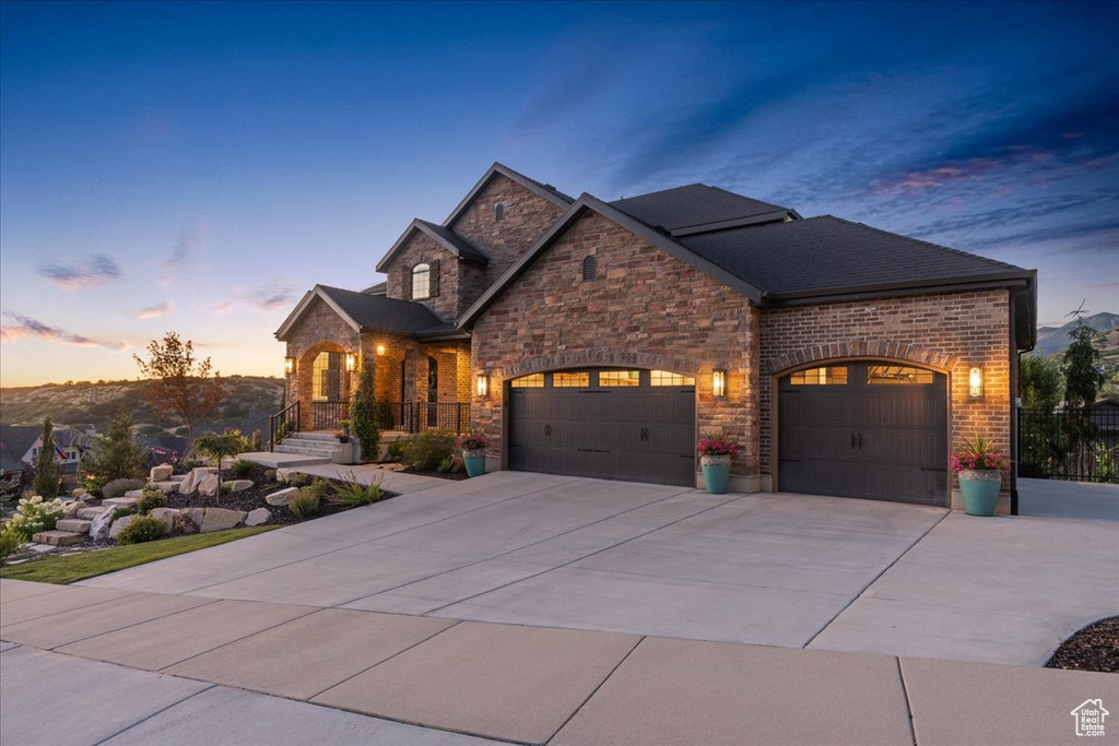 View of front of property featuring a garage, driveway, and stone siding