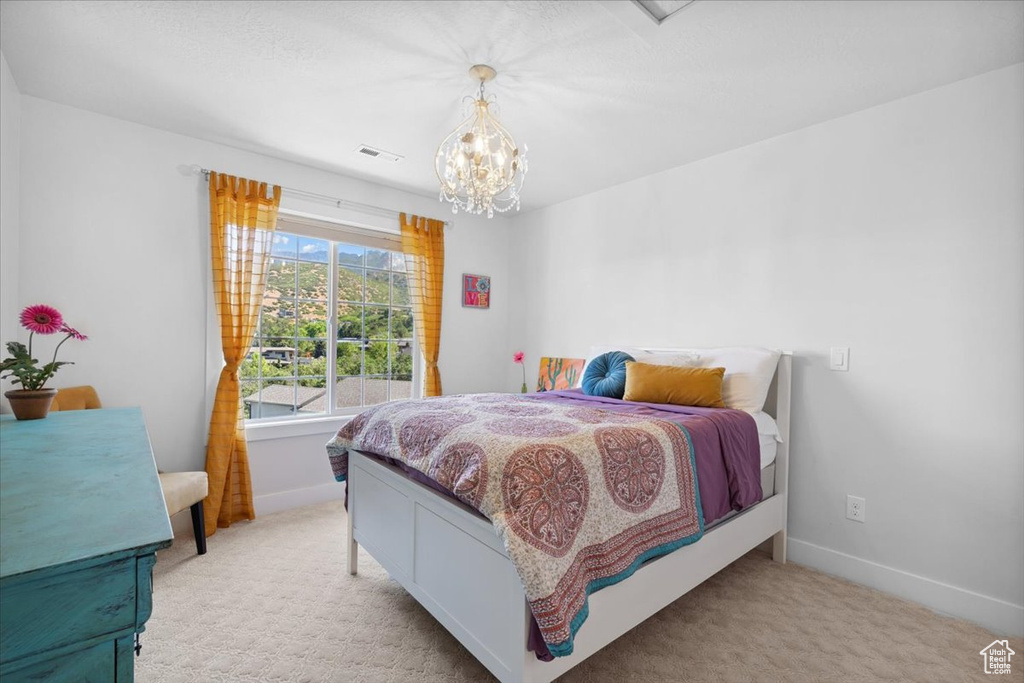 Bedroom with a chandelier and light colored carpet