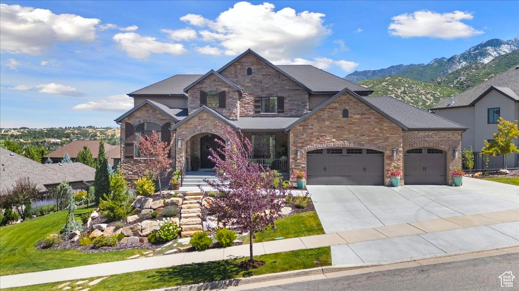 View of front facade with concrete driveway, an attached garage, a mountain view, and stone siding
