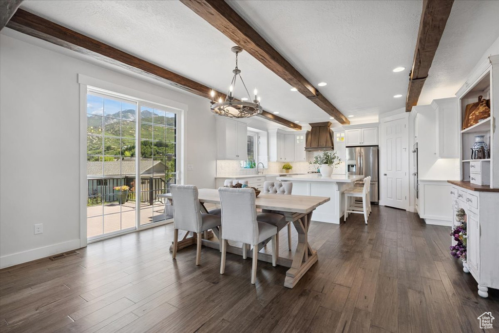Dining space with beam ceiling, a chandelier, dark wood-style flooring, and recessed lighting