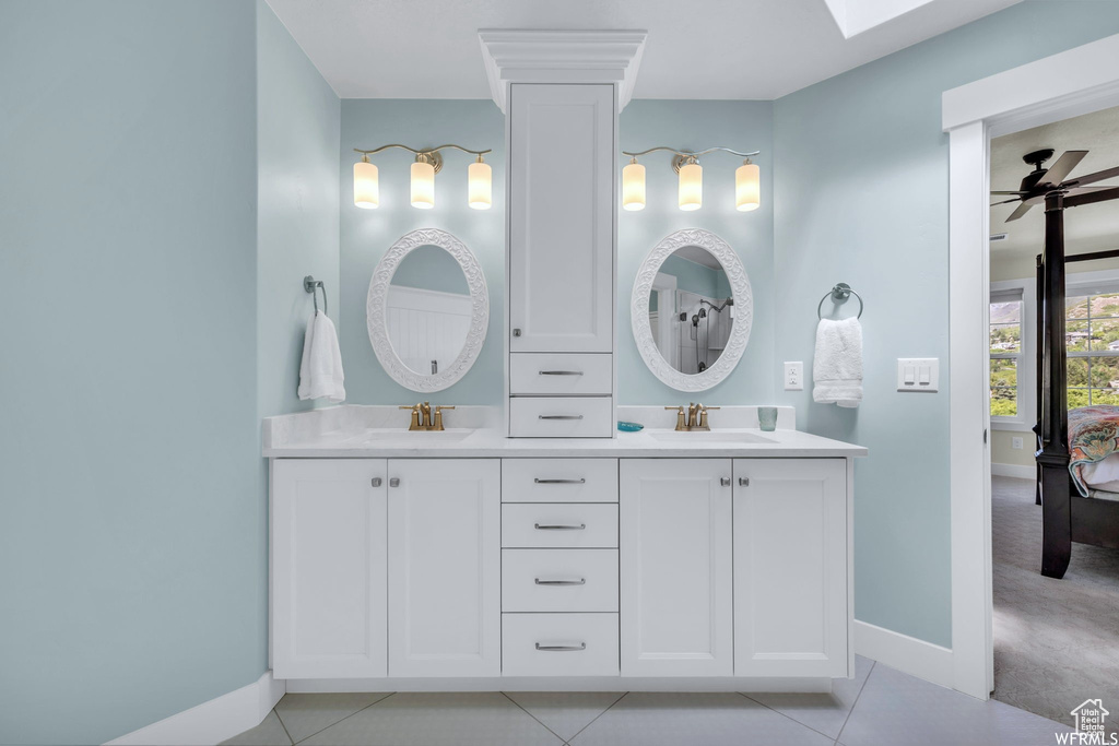 Full bathroom featuring double vanity, ceiling fan, tile patterned floors, and a skylight