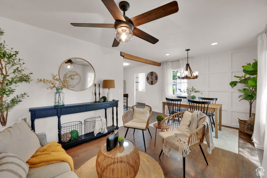 Living room with a ceiling fan, wood finished floors, a decorative wall, recessed lighting, and a chandelier