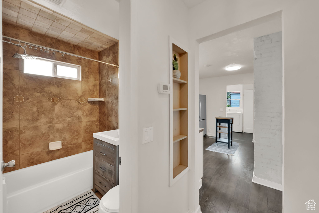 Bathroom with healthy amount of natural light, shower / bath combination, wood finished floors, and vanity