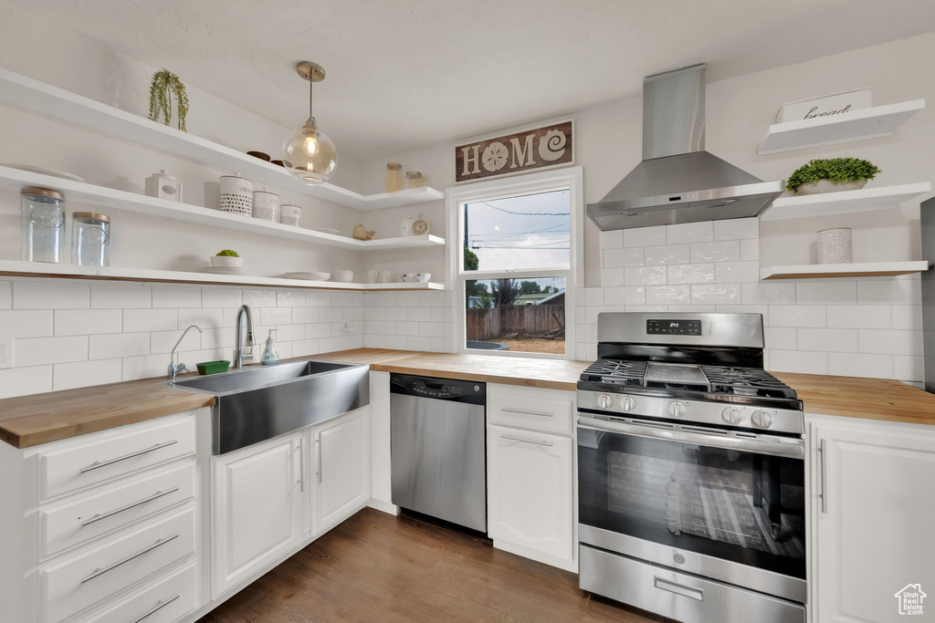 Kitchen featuring wooden counters, wall chimney exhaust hood, and stainless steel appliances