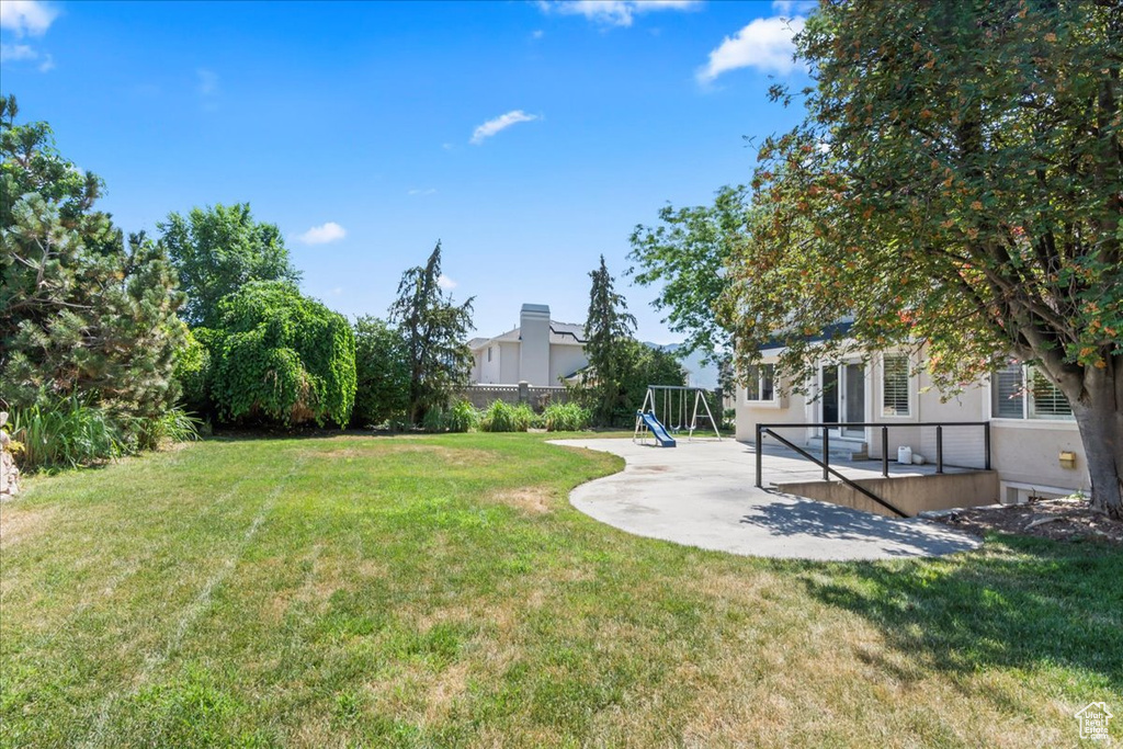 View of yard featuring a wooden deck and a patio area