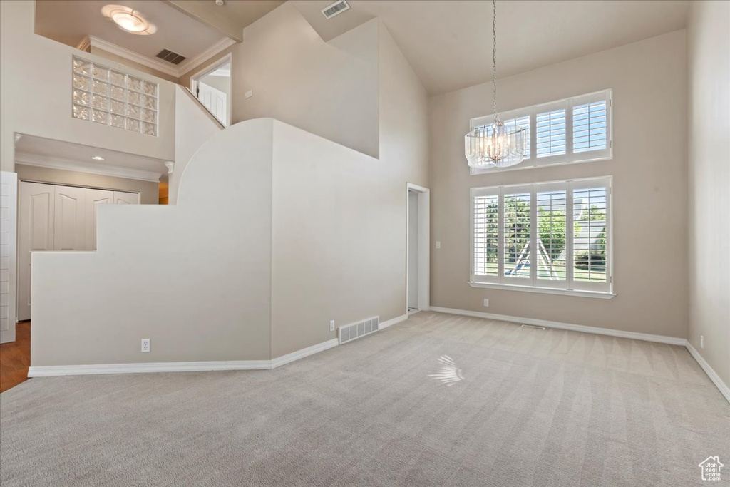 Unfurnished living room featuring a high ceiling, a chandelier, and carpet