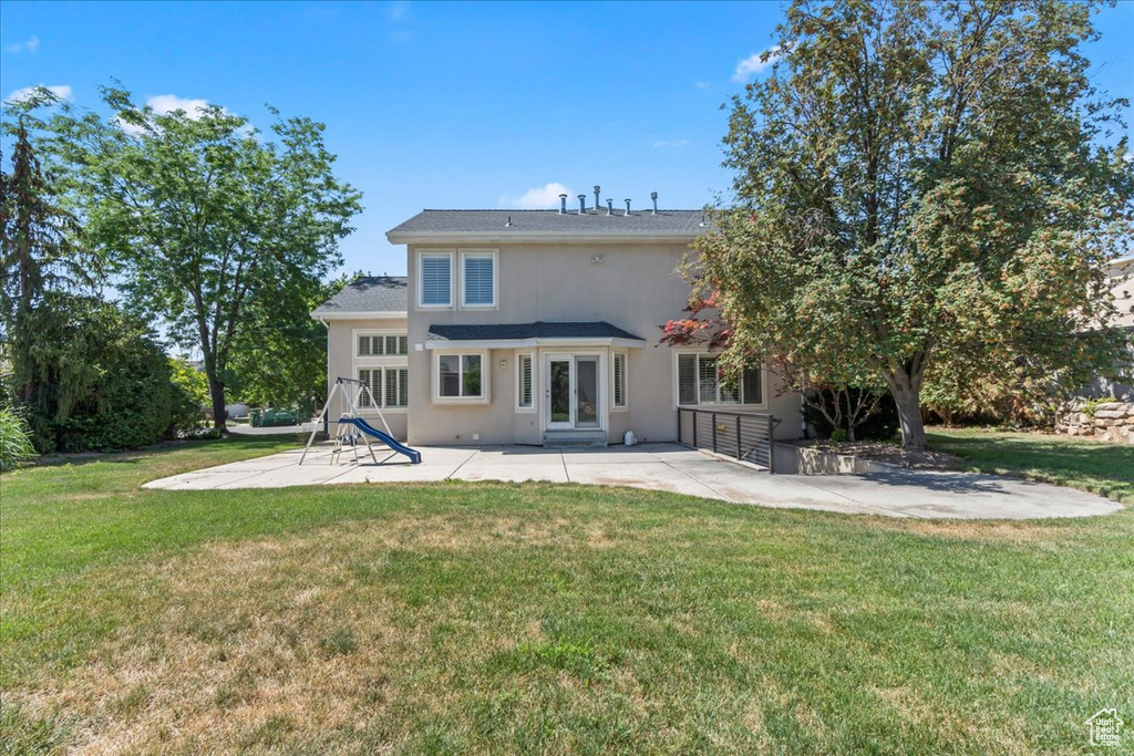Back of house featuring a patio area, a lawn, and stucco siding