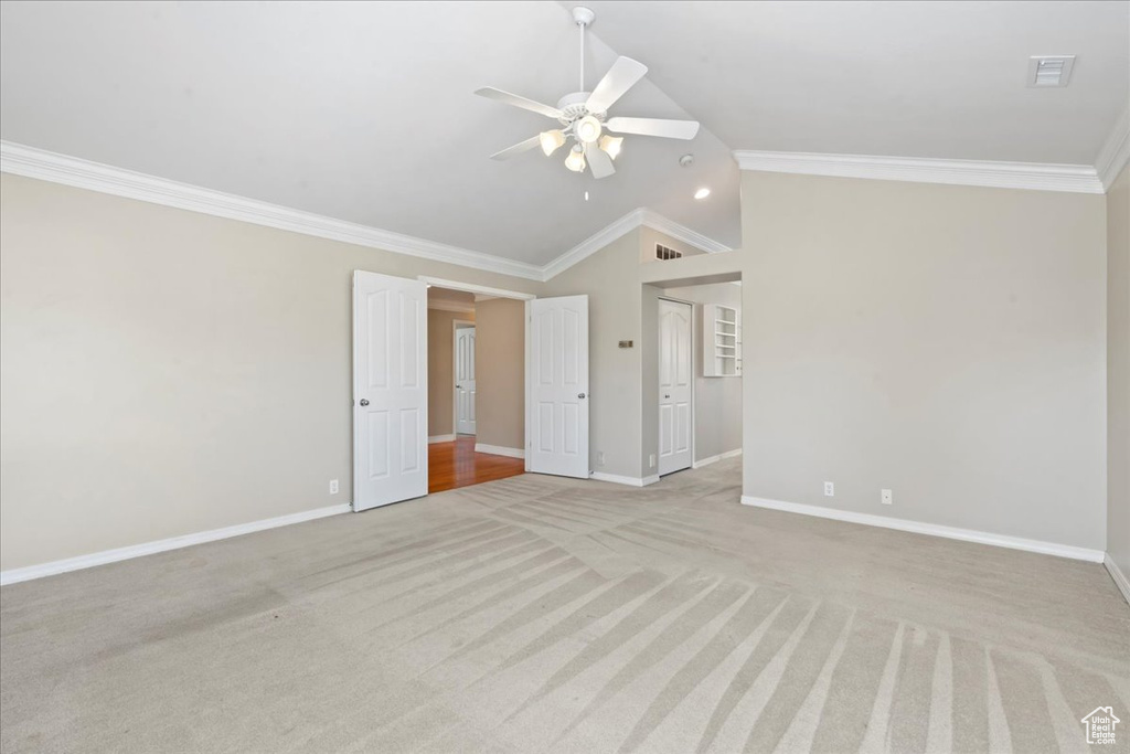 Unfurnished room with lofted ceiling, ceiling fan, light colored carpet, and ornamental molding