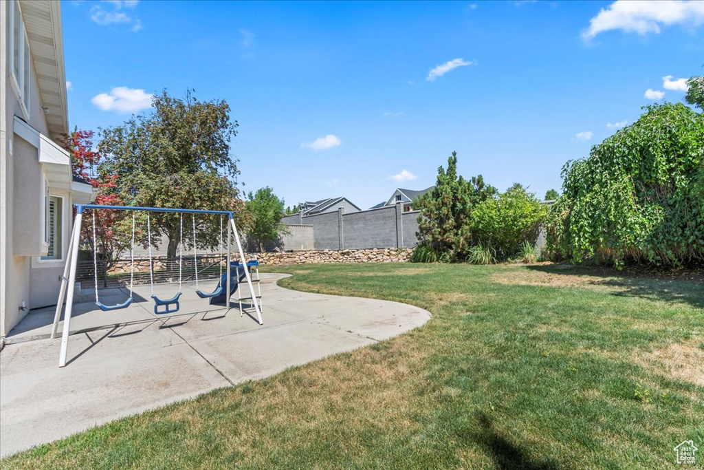 Fenced backyard with a playground and a patio