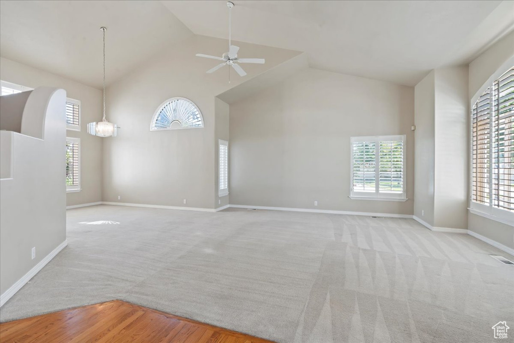 Unfurnished living room with high vaulted ceiling, a ceiling fan, plenty of natural light, and carpet floors