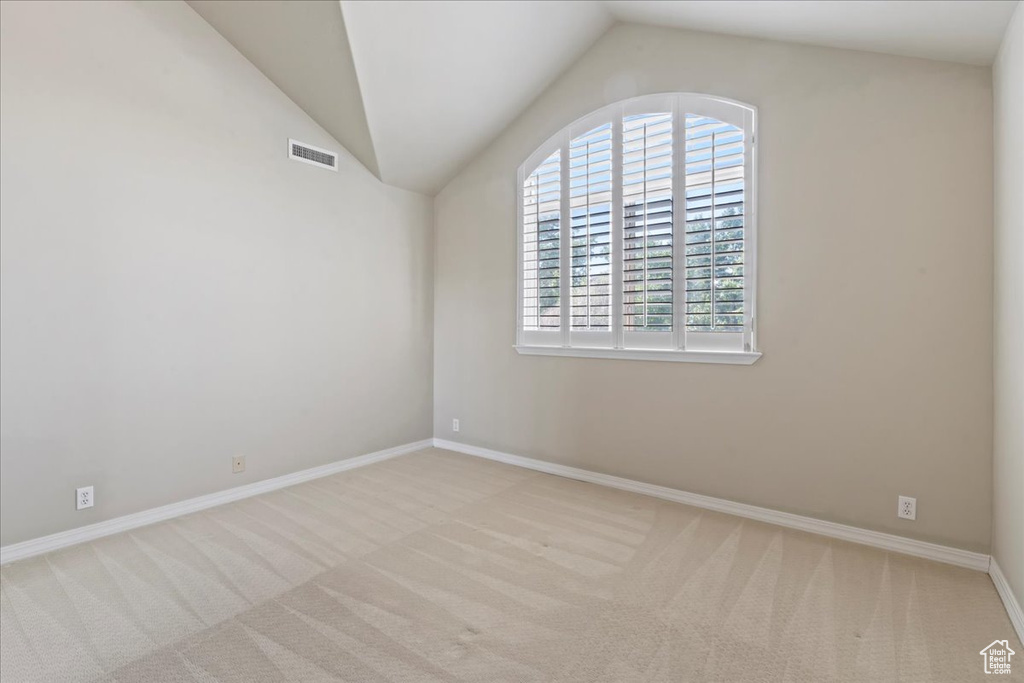 Unfurnished room featuring carpet flooring and vaulted ceiling