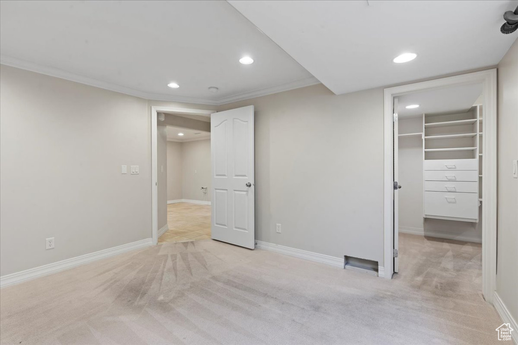 Unfurnished bedroom featuring recessed lighting, light carpet, a walk in closet, and crown molding
