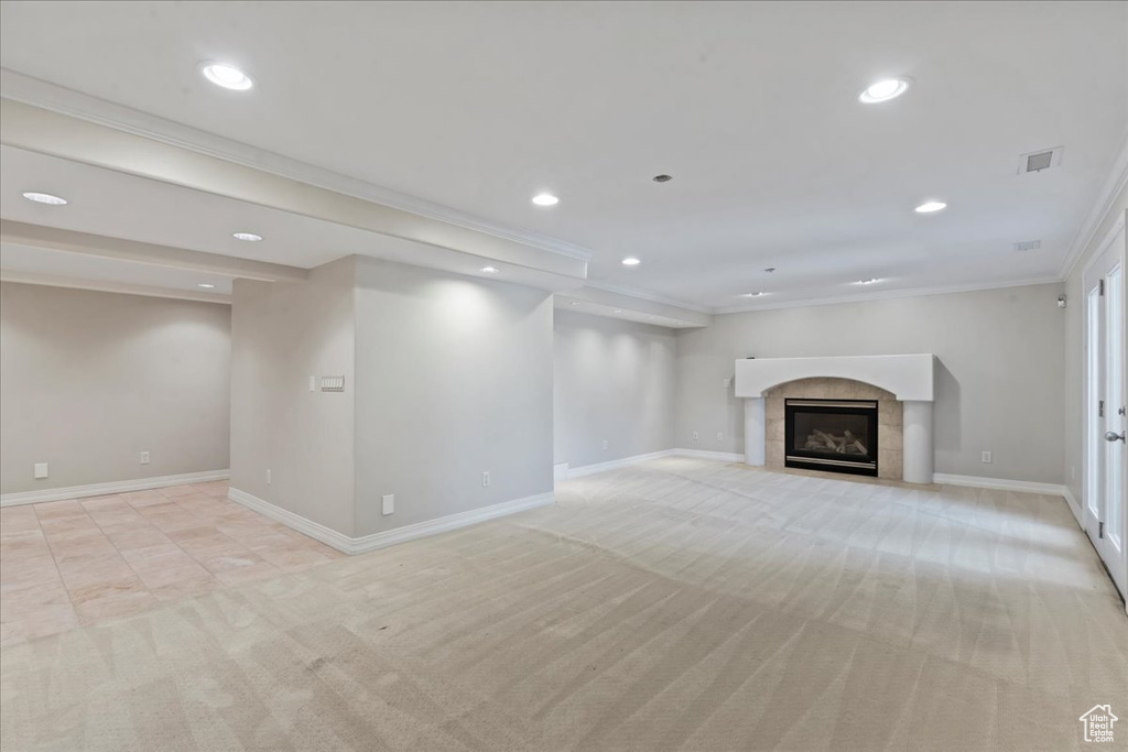 Unfurnished living room featuring light colored carpet, recessed lighting, crown molding, and a tile fireplace